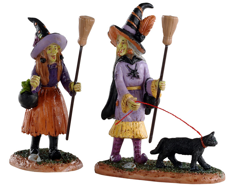 Lemax Spooky Town Witches Night Out, Set of 2 #02907 at Eerie Emporium - Two green faced witches dressed in purple, hold their brooms while walking a black cat.