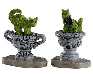 Lemax Spooky Town Haunted Topiary, Set of 2 #04714 at Eerie Emporium - two ornate stone outdoor planters, one with a spider carved into it and the other with a gargoyle, hold carved hedges that look like creepy cats.