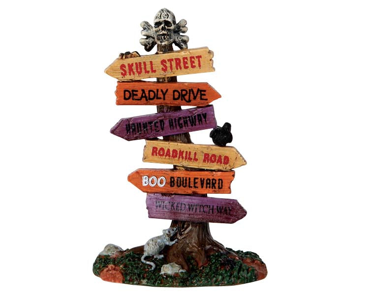 Lemax Spooky Town Scary Road Signs #64054 at Eerie Emporium - a tall skinny tree stump is topped with a skull and crossbones while numerous spooky signs were nailed into the stump below.