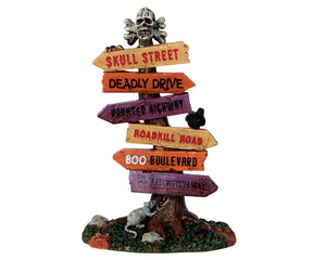 Lemax Spooky Town Scary Road Signs #64054 at Eerie Emporium - a tall skinny tree stump is topped with a skull and crossbones while numerous spooky signs were nailed into the stump below.