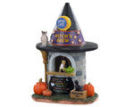 A small stone building shaped like a witch hat has a witch serving coffee from it. An owl, black cat and pumpkins add to the ambiance.