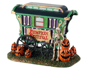 A green and purple wagon with bones has a sign that reads Pumpkin Festival. Next to the wagon are multiple jack o' lanterns. 