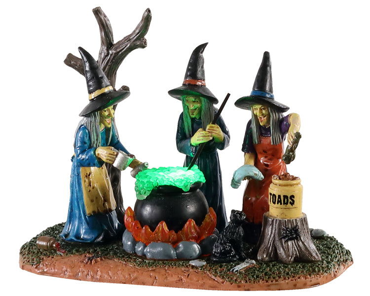 Three witches huddle around a boiling cauldron full of glowing green liquid. A tree stump with a spider on it and a jar that reads TOADS sit in the foreground while a creepy tree is behind them.