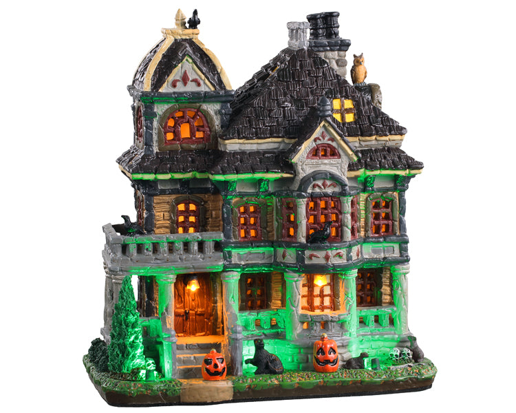 A Spooky old mansion glows green and yellow while two jack-o'-lanterns, a black cat and various skulls warn potential visitors.