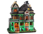 A Spooky old mansion glows green and yellow while two jack-o'-lanterns, a black cat and various skulls warn potential visitors.