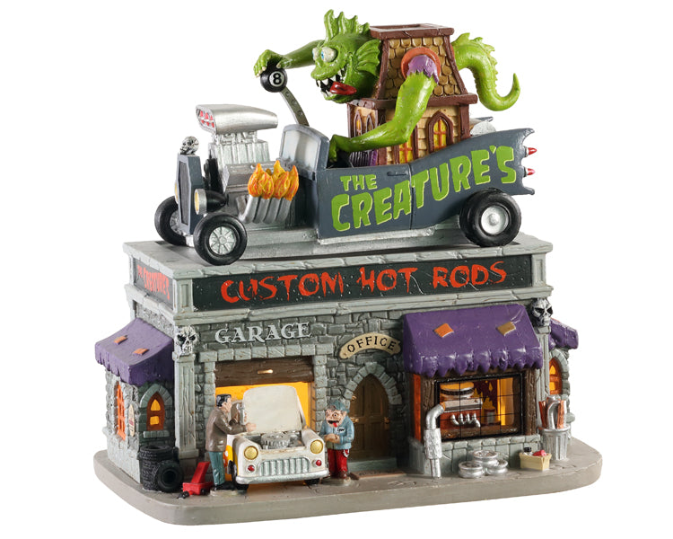 A business called The Creature's Custom Hot Rod Shop has a large monster driving a hot rod on top and monsters working on cars throughout the stone building.