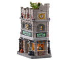 A grey stone building has two large signs in black and green that read Dragon's Lair Potions and Spells. On top of the building is a large Green Dragon, while down below are pumpkins, gothic lamp posts and bottles of potions.
