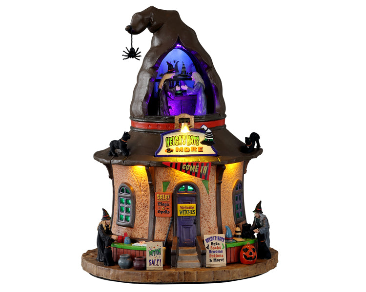 
            
                Load image into Gallery viewer, A witch hat shaped building called Helga&amp;#39;s Hats &amp;amp; More has multiple witches working on creating hats. The building has multiple yellow and blue colored lights.
            
        