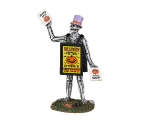 A skeleton wearing a purple top hat holds signs in each had that reads Halloween Festival. He is wearing a large sign that is yellow and also reads Halloween Festival with a jack o lantern on it.
