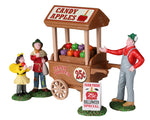 A man sells candy apples out of his wooden cart to young trick or treaters.