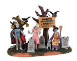 Three Skeletons are dressed in costumes in a cemetery with a sign a sign that reads "Halloween Costume Party! October 31". There's a skeleton dog in front of one of the skeletons and string lights handing from one of the trees behind the trio.