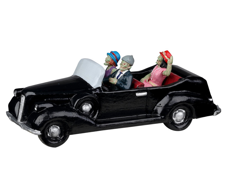Lemax Spooky Town Roaring Roadster #23603 - three ghouls, two woman and one man, ride in a 1920s style black car with red seats. The trio are all dressed well for a night out.