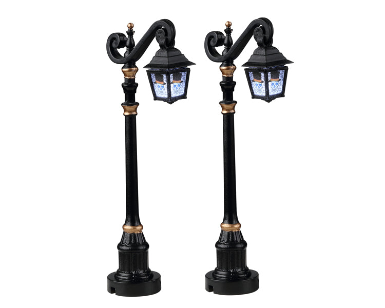 Black and gold gothic street lamps have skeletons in the lamp section.
