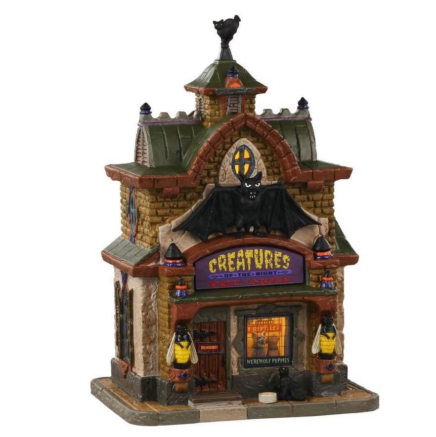 Lemax Spooky Town Creatures Of The Night Pet Shop #35013 - A Stone building with a green roof has a large Bat the front of it while puppy Werewolf's peak out the front window and killer bees sit on the left and right of the structure.  