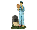 Lemax Spooky Town Wake The Dead #32191 - A zombie wearing light blue pajamas looks into a mirror while standing above their tombstone which has a tan pillow resting on it.