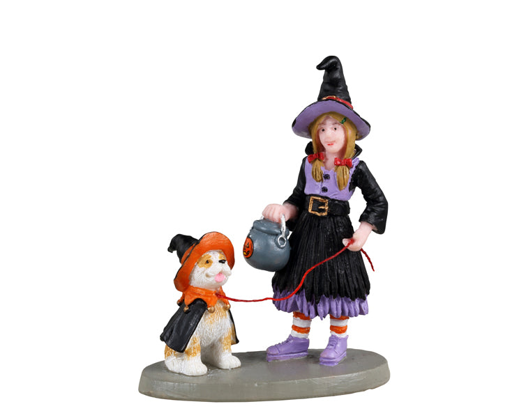 Lemax Spooky Town No Chocolate For You! #32198 - A girl wearing a light purple and black witch costume holds a cauldron trick or treat bucket in one hand and a leash attached to her puppy that is also wearing a costume.
