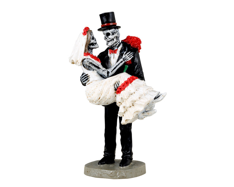 
            
                Load image into Gallery viewer, Lemax Spooky Town Day Of The Dead Bride &amp;amp; Groom #32201 - A skeleton wearing a black suit and top hat with a red bowtie holds his wife on their wedding day.
            
        