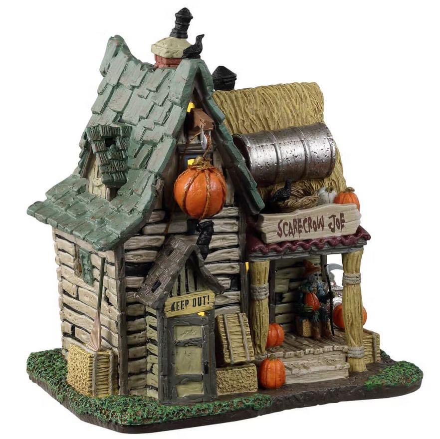 Lemax Spooky Town The Last Straw: House Of The Scarecrow #35015 - a dilapidated brown cabin with a green roof has a sign on the door that reads "KEEP OUT!" while a skeleton sits on the front porch guarding the home. 