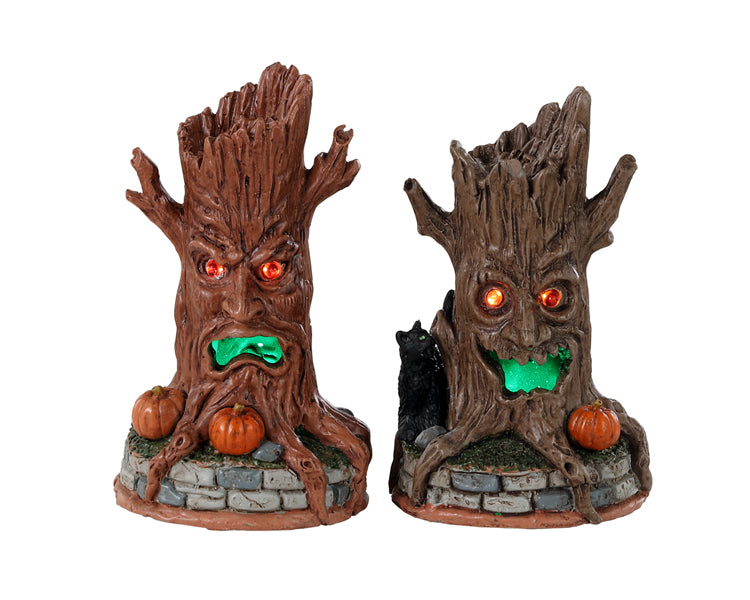Lemax Spooky Town Haunted Tree Trunks #34072 - two sinister looking tree stumps rest atop brick platforms while jack o lanterns and black cats rest at their bases.