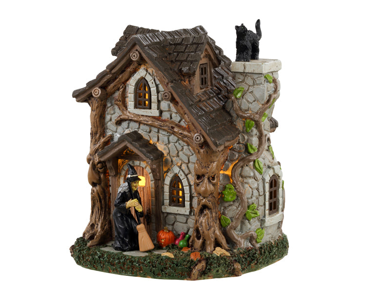 Lemax Spooky Town Wanda's Cottage #34079 - A small stone home in covered by a wicked tree that has a face while a witch sweeps out front and a black cat sits on the chimney.