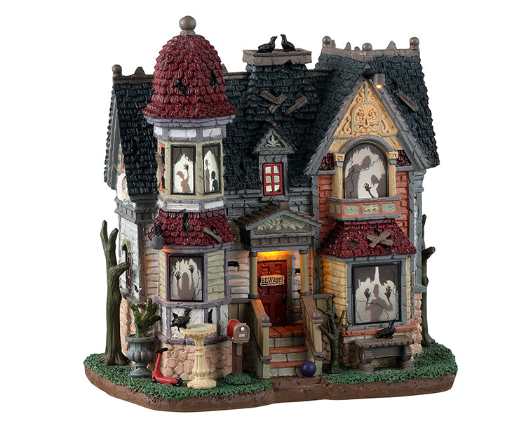 Lemax Spooky Town The House Of Shadows #35004 - A dilapidated house with red and black shingled roofs depicts numerous shadowed ghosts and monsters in the windows.
