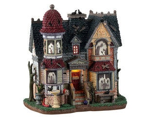 
            
                Load image into Gallery viewer, Lemax Spooky Town The House Of Shadows #35004 - A dilapidated house with red and black shingled roofs depicts numerous shadowed ghosts and monsters in the windows.
            
        