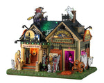 Lemax Spooky Town Samantha's Supernatural #35005 - A forest green and muted yellow wooden house is covered in Halloween yard decorations including a witch, ghost, mummy, big foot, Frankenstein, ghosts, a mummy and more.