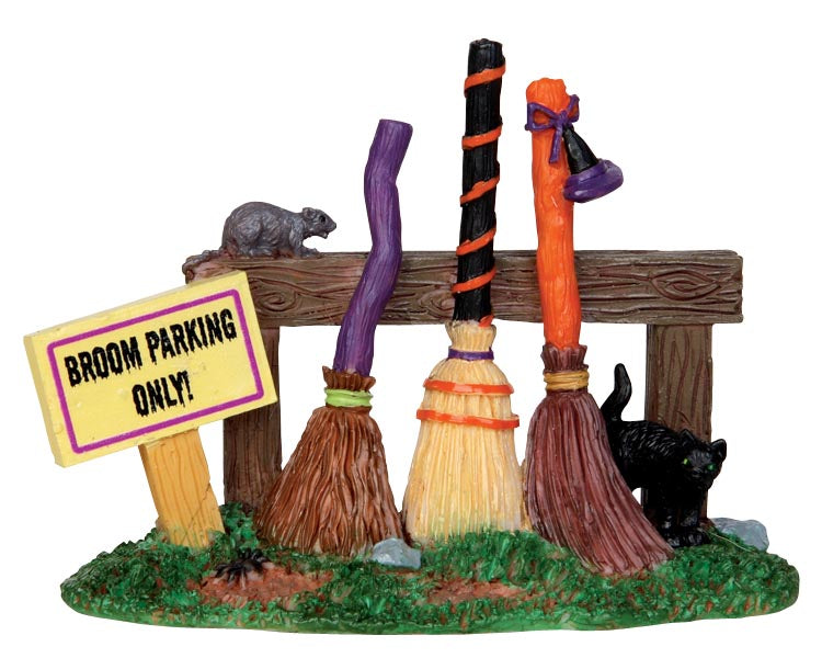 Three brooms, one purple, one orange and one a combination of black and orange lean against a wood structure while a black cat and mouse hangout in the area.