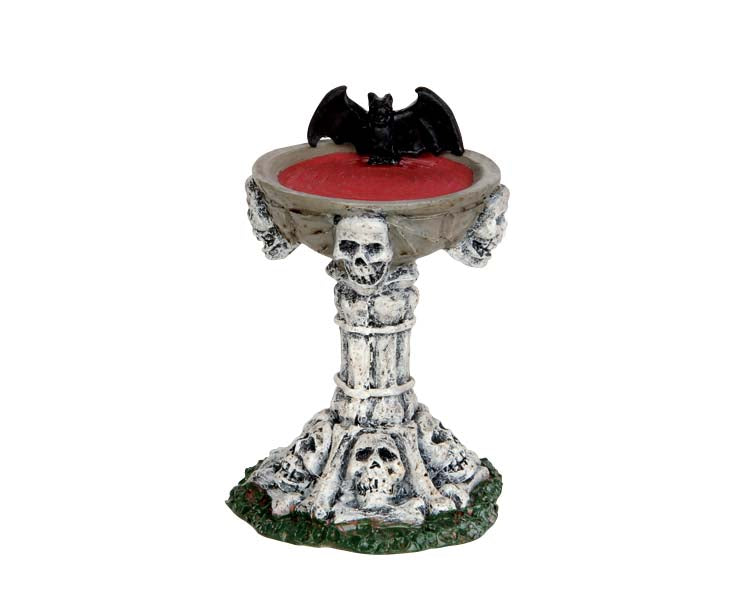 A birdbath made of skulls and bones is full of blood. A bat rests on the edge of the bath.