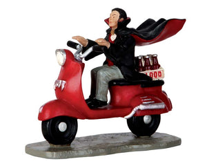 
            
                Load image into Gallery viewer, A caped vampire drives a bright red moped with a six pack of bottles full of blood on the back.
            
        