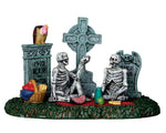 two skeletons have a picnic in a cemetery while a vulture waits its turn to eat. 