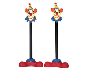 
            
                Load image into Gallery viewer, 2 lamp posts with large red clown shoes at their base, are illuminated by creepy clown faces up top.
            
        