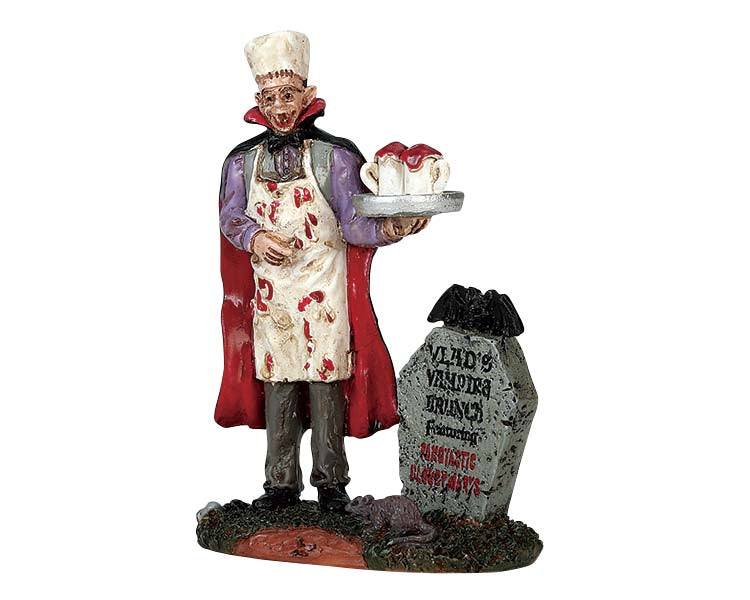 
            
                Load image into Gallery viewer, An evil vampire covered in blood, wearing a cape and chefs hat holds a tray with two mugs full of blood while he stands next to a tombstone.
            
        