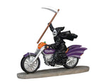 A grim reaper holds a scythe above his head in his right hand while driving a purple motorcycle with a pumpkin between the handle bars. 