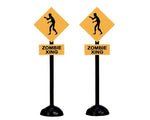 Two black and gold zombie crossing road signs. 