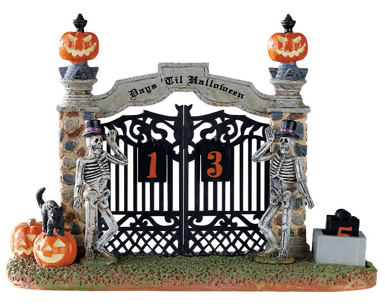 
            
                Load image into Gallery viewer, A gothic stone and iron fence topped by pumpkins is guarded by two skeletons wearing black and purple top hats. A sign on top of the fence reads Days Til Halloween with the number of days listed below.
            
        
