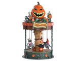 Children dressed in costumes ride on animals and spin around this carnival ride. A large pumpkin sits on top of the ride with multiple skeletons and smaller pumpkins.