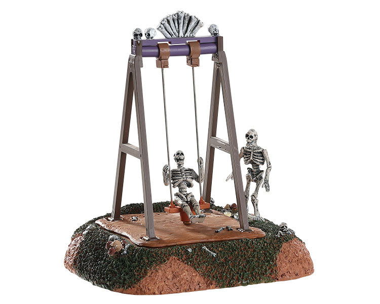 One skeleton sits on a large swing while another skeleton looks on.