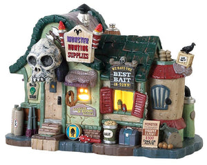 
            
                Load image into Gallery viewer, A Small building with a sign that reads &amp;quot;Monster Hunting Supplies&amp;quot; is covered in various supplies like garlic, explosives, weapons and more. The roof is green and there is a large skull over the door while a yellow glow emits from the inside.
            
        