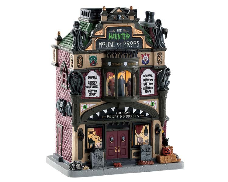 A gothic museum made of red brick has green roof shingles, gargoyles and tombstones. On the front of the structure is a large sign that reads The Haunted House of Props.
