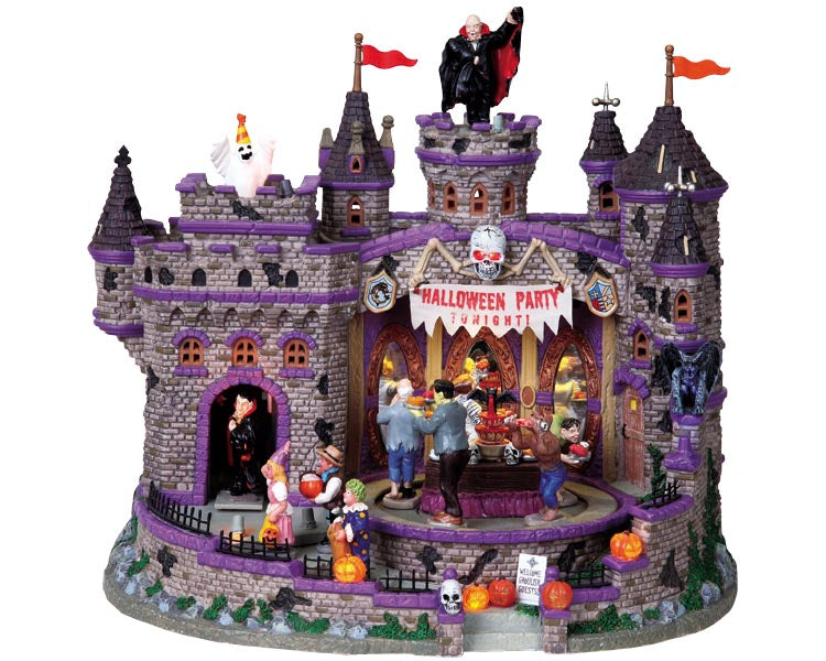  A large stone castle is filled with monsters. Party revelers move around a buffet table, a ghost emerges near the roof of the castle and a vampire host moves forward from the castle doorway.