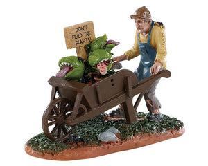 A creepy old man pushes a cart of man eating plants with a sign reading don't feed the plants!