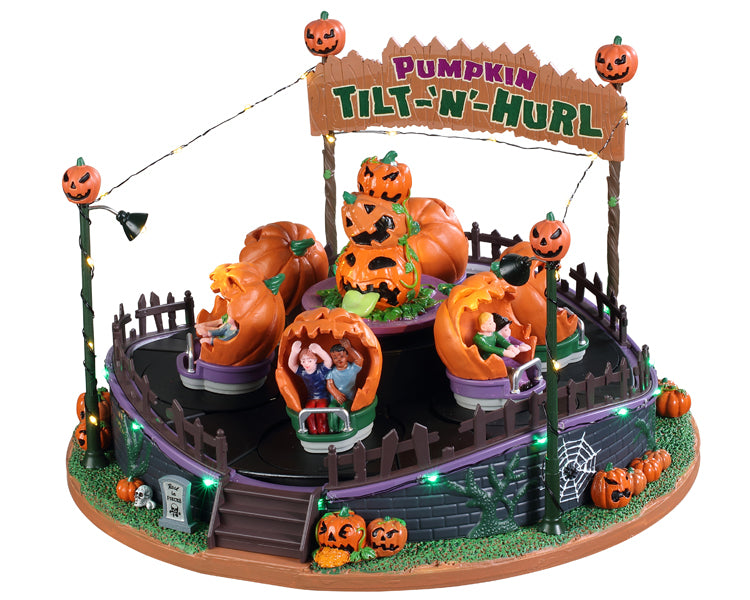 This large carnival ride's main attraction is pumpkin carts full of enthusiastic riders. The carts spin on a revolving floor while string lights glow all around the ride. There's additional pumpkins in front of the ride and a large sign that reads Pumpkin Tilt-N-hurl in back.