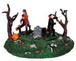 A vampire slayer with a wooden stake chases a vampire through a graveyard with two creepy trees and a jack-o'-lantern.
