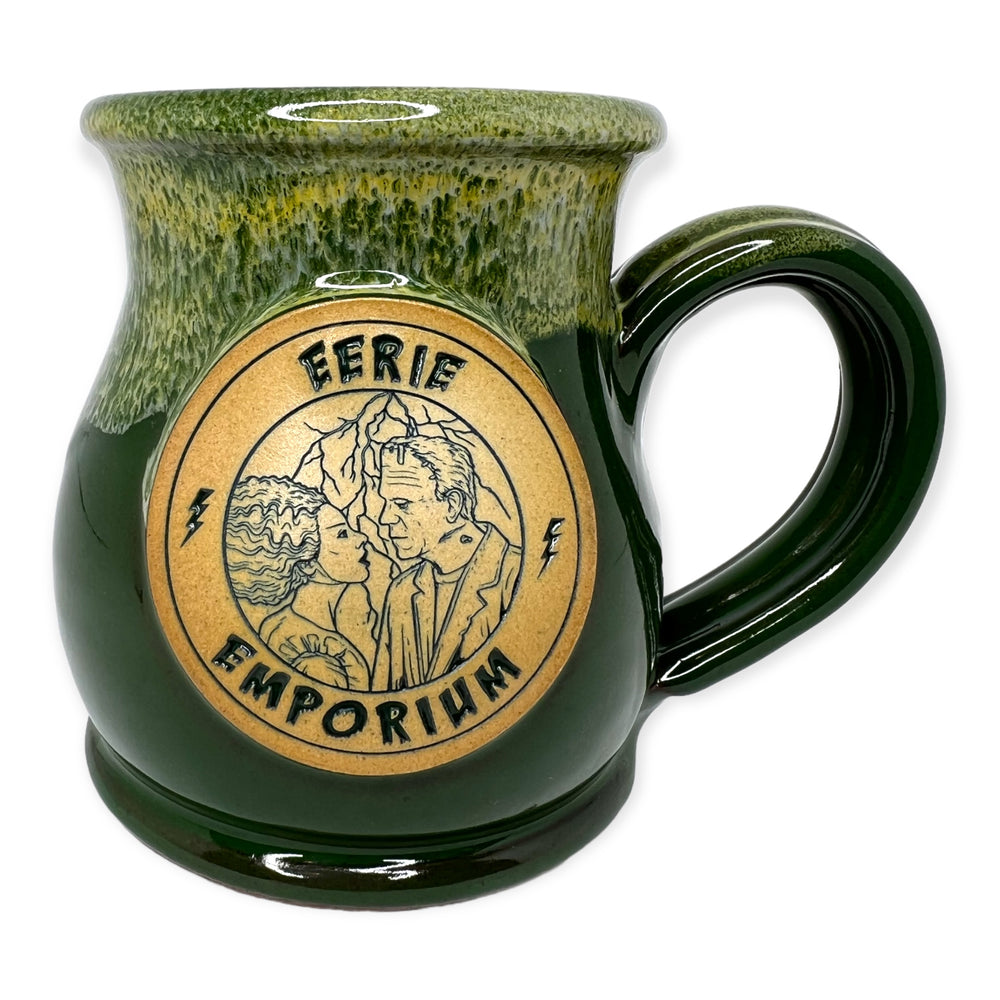 
            
                Load image into Gallery viewer, Eerie Emporium Frankenstein Coffee Mug In Electric Drip Color Scheme - Frankenstein and Frankenstein&amp;#39;s Bride stare longingly into each others eyes while lightening bolts usher in darkness around them on this multiple shades of green drip glaze coffee mug.
            
        