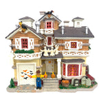 Retired Lemax Spooky Town Franklin Residence #45004 - A brown and yellow neighborhood  house is decorated for Halloween with jack o lanterns, a scarecrow, tombstones and more.