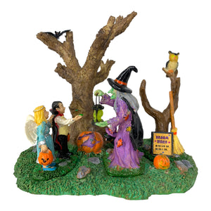 
            
                Load image into Gallery viewer, Retired Lemax Spooky Town Broom Rides #93716 - A witch holding a lantern offers broom rides to two costumed children in a forest.
            
        